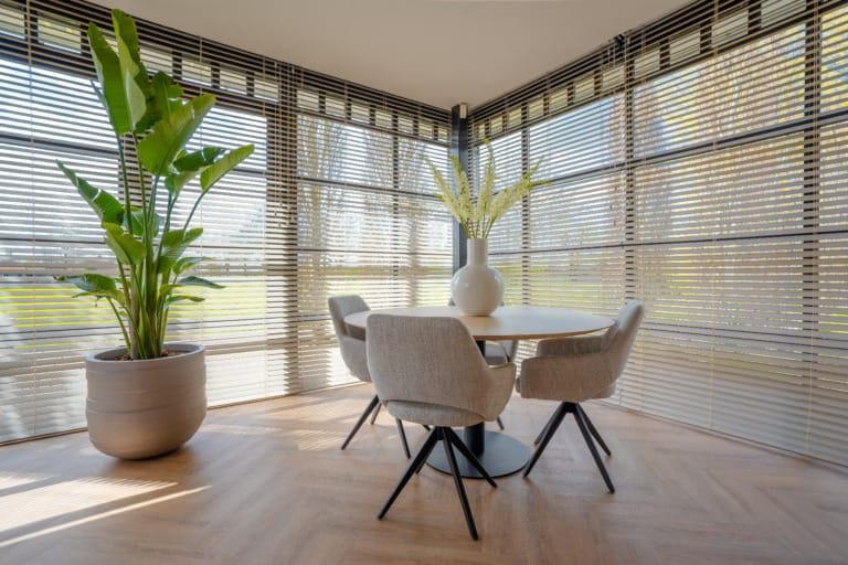 B&E Homestyling- Houten jaloezie 2 Houten jaloezieën voor een hoekraam in een lichte eethoek