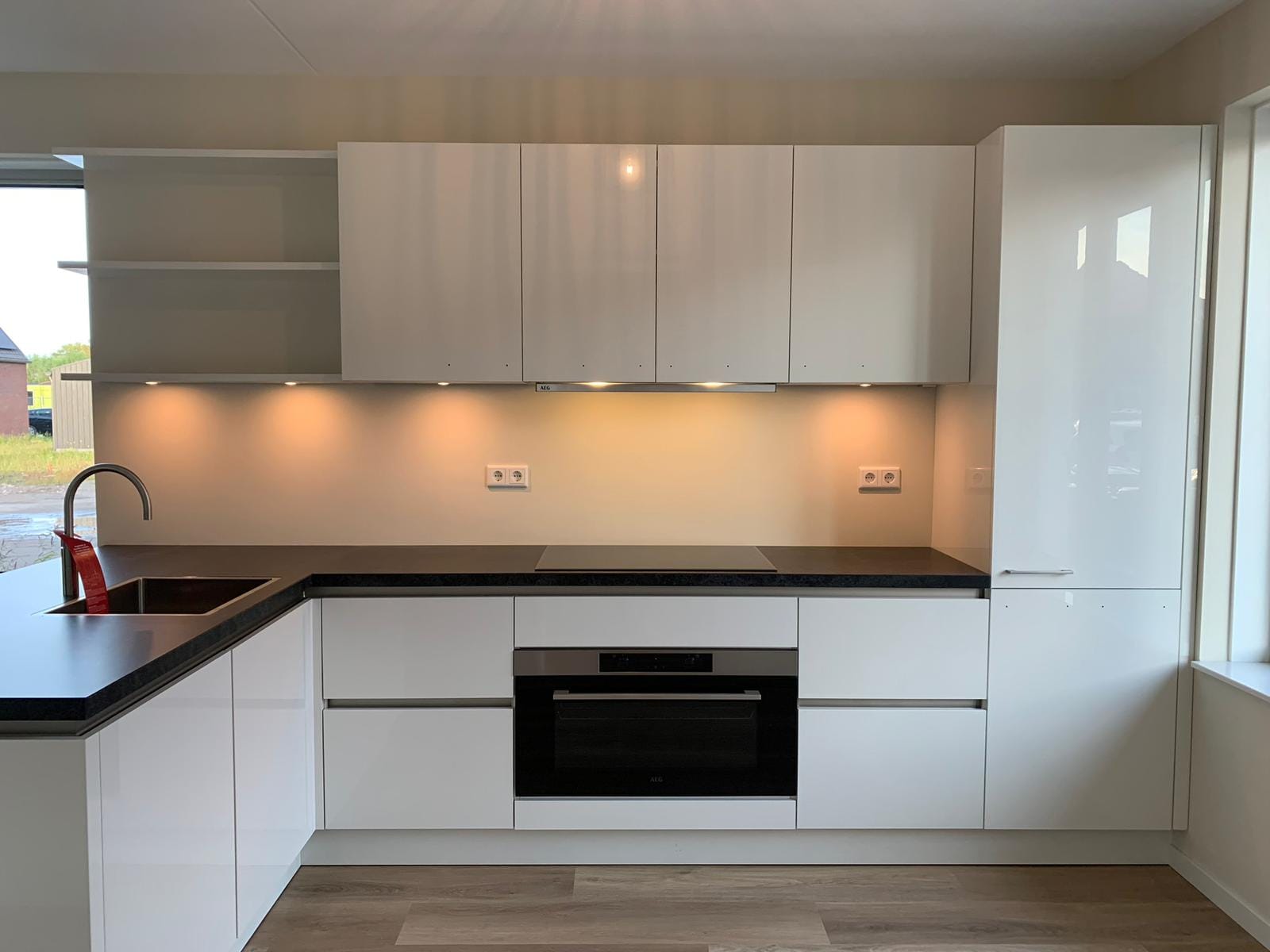 Witte hoogglans keuken met verlichte bovenkasten