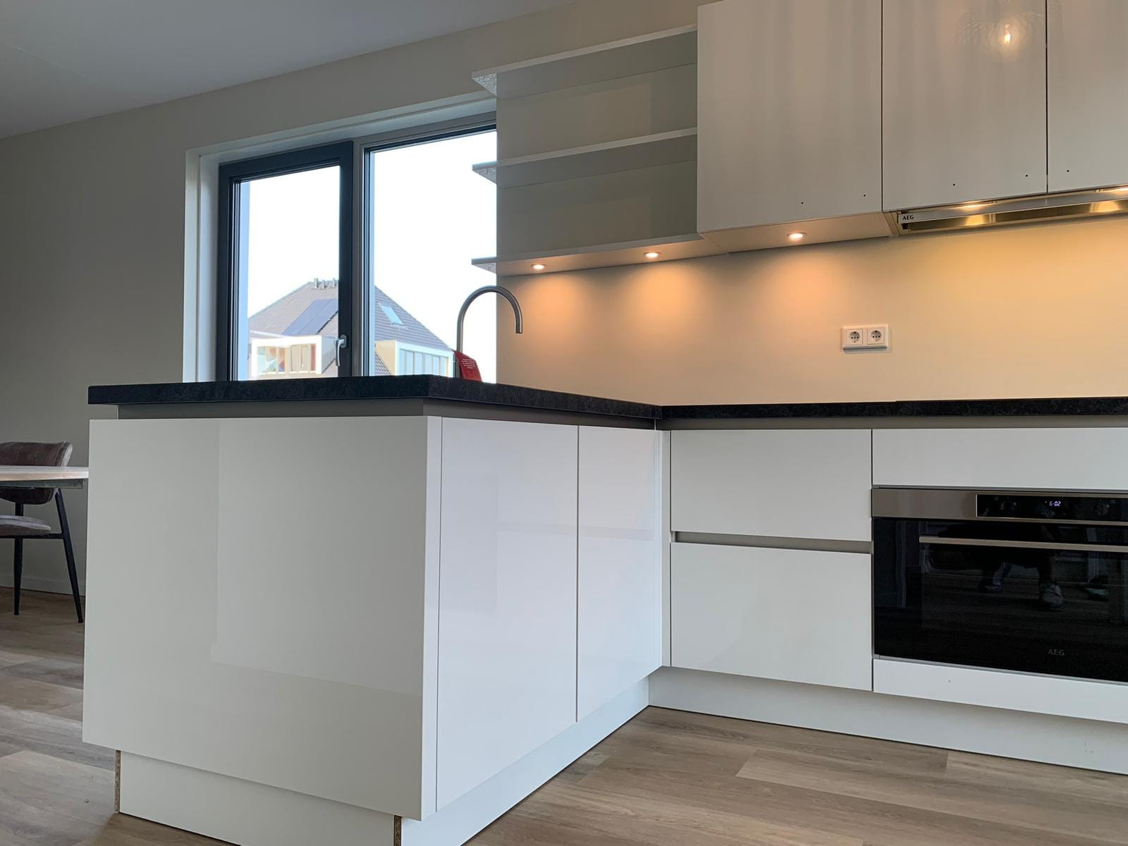 Witte keuken met kookeiland en verlichte bovenkasten