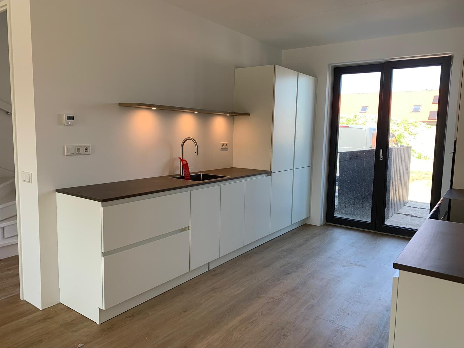Witte greeploze keuken met donker werkblad en tuindeuren