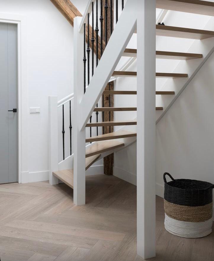 Open houten trap met witte trapwangen en zwarte spijlen Open houten trap met witte trapwangen en zwarte spijlen